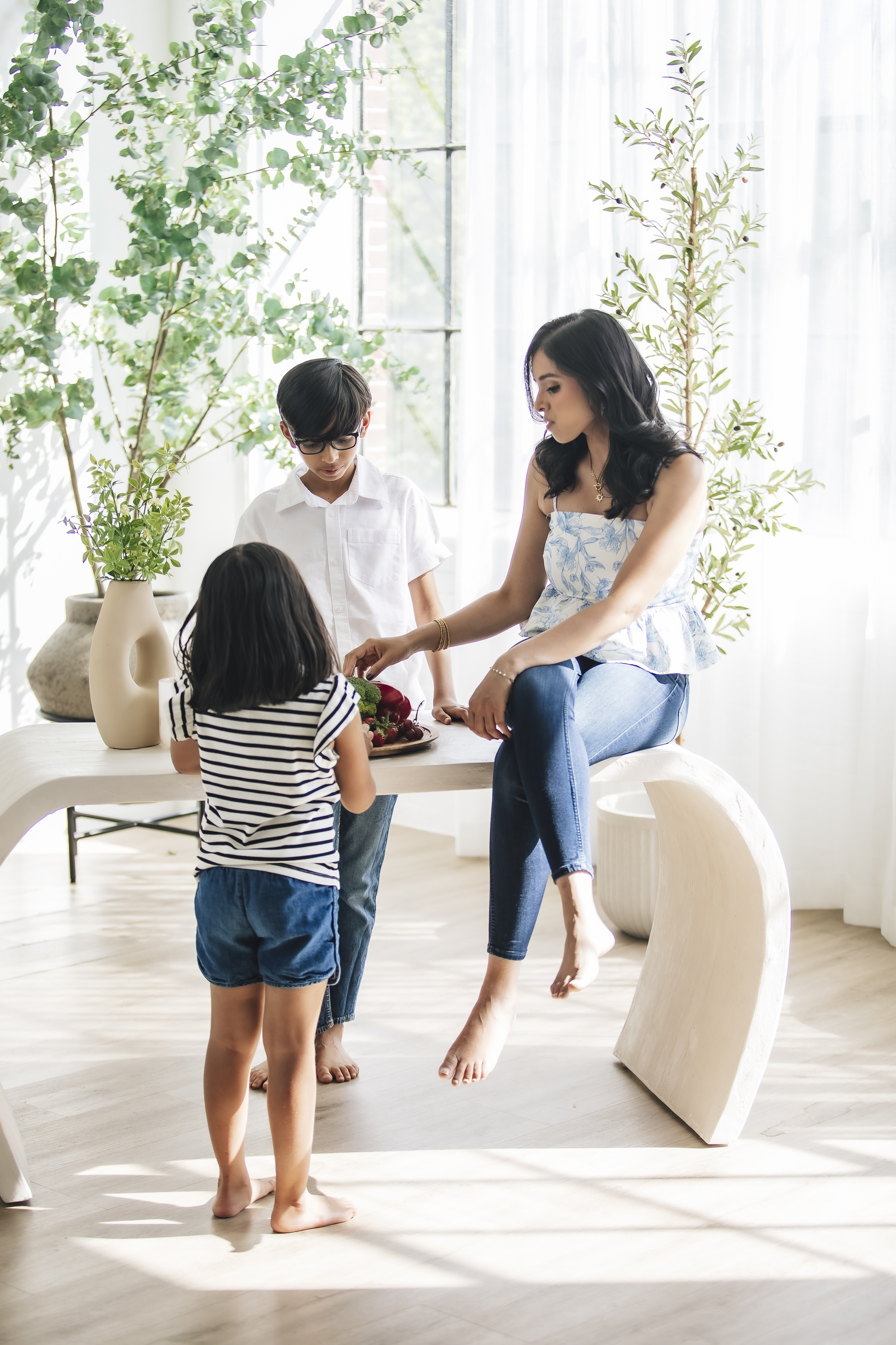Varsha with her children in a bright, airy room